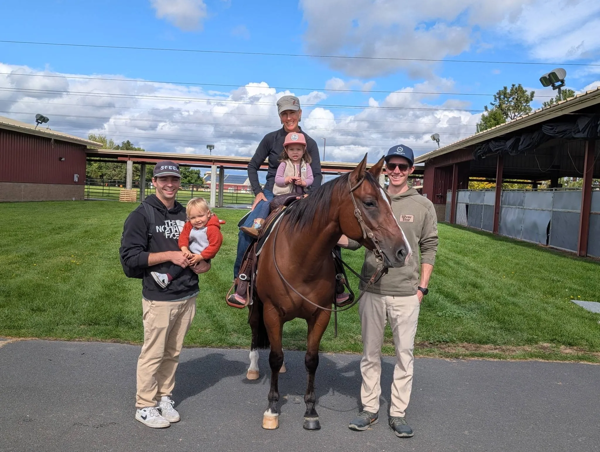 Ben, his brother-in-law holding a toddler, his nephew, and Aunt Kim with Parker in the saddle, all posing outside with a bay horse named Otto