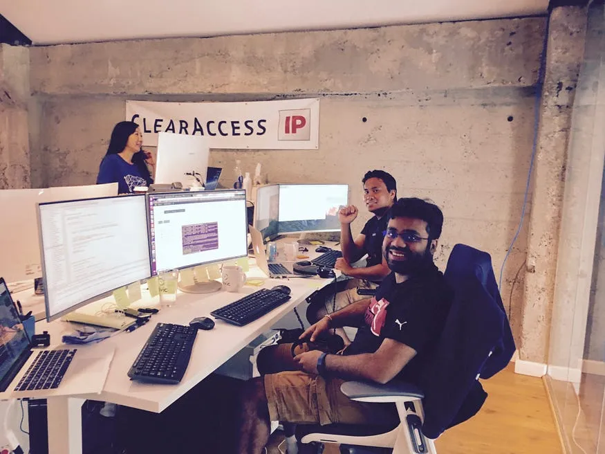 The ClearAccessIP team working at desks in their Palo Alto startup office beneath a ClearAccessIP banner