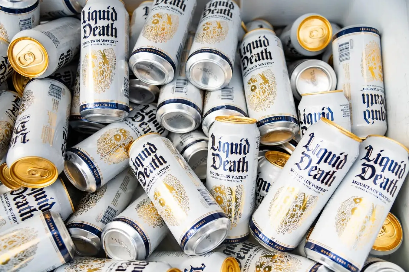 A cooler packed full of white-and-gold Liquid Death Mountain Water cans