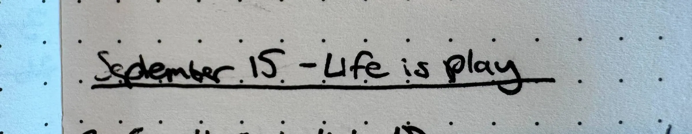 Handwritten note on dot-grid paper reading “September 15 - Life is play”