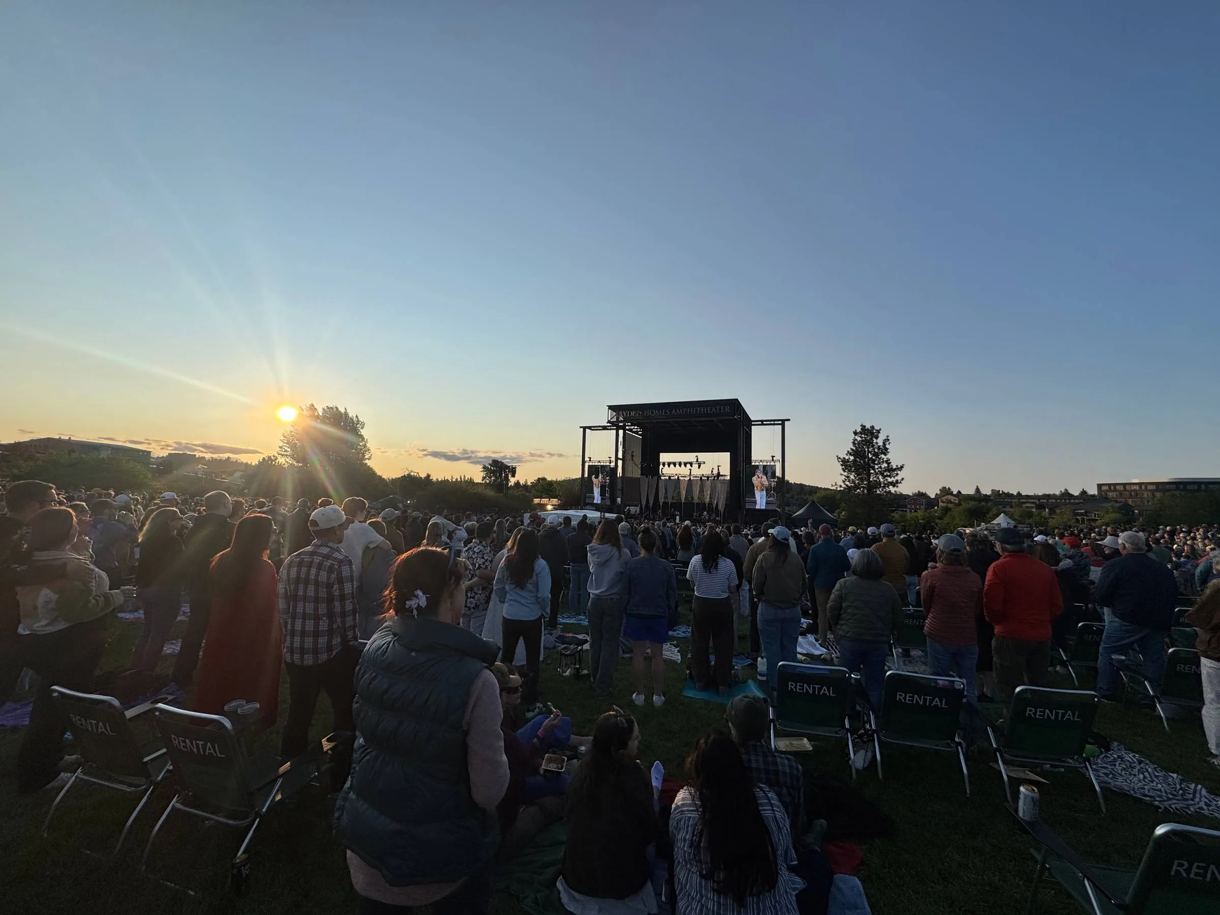 Crowd at an outdoor amphitheater watching Leon Bridges perform at sunset