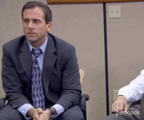 Michael Scott from The Office sitting in a chair, slowly considering something
