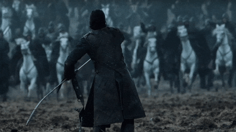 Animated GIF of a lone sword-wielding warrior standing his ground as a cavalry charges toward him across a muddy battlefield