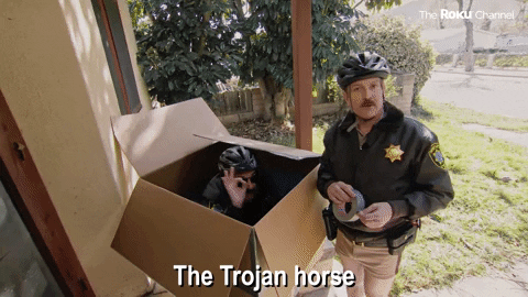 “The Trojan horse” comedy GIF of a police officer hiding inside a cardboard box on a doorstep